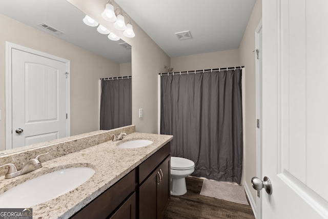 bathroom featuring double vanity, wood finished floors, a sink, and visible vents