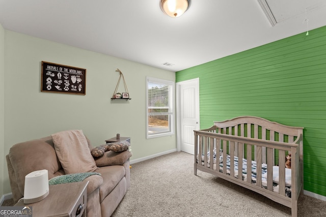 carpeted bedroom with visible vents, a crib, attic access, and baseboards