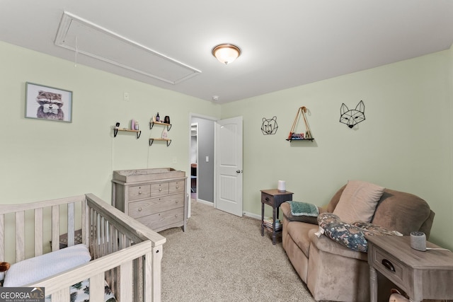 bedroom featuring a nursery area, carpet floors, attic access, and baseboards