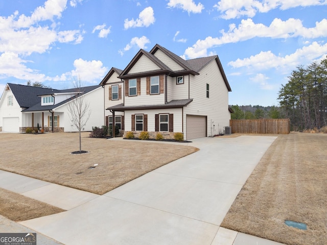 view of front facade with central AC unit, a garage, fence, driveway, and stone siding