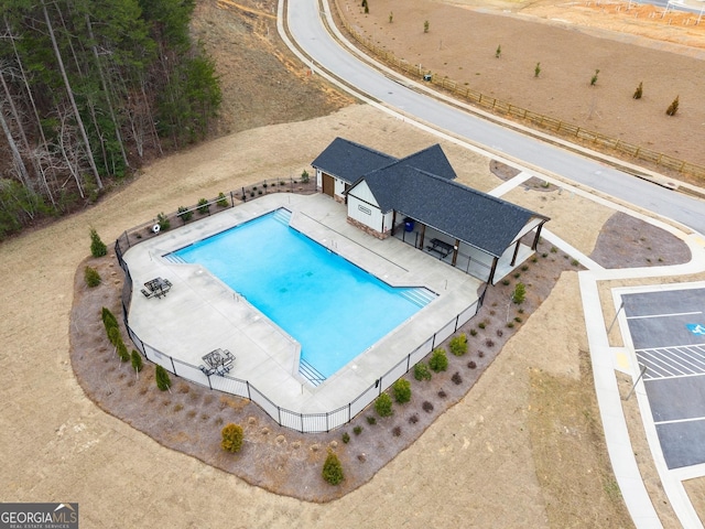 community pool with a patio area and fence