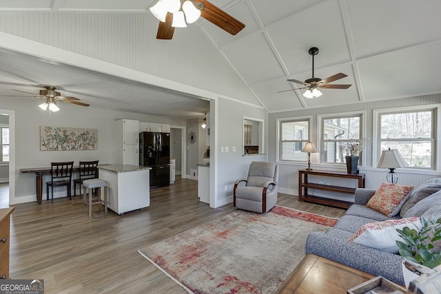 living area featuring light wood finished floors, baseboards, and high vaulted ceiling