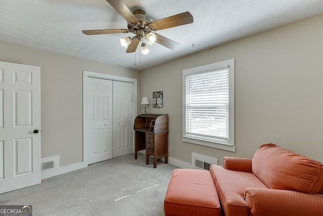 living area featuring visible vents, light carpet, a textured ceiling, and baseboards