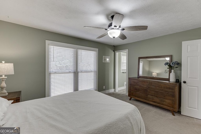 bedroom with light carpet, ceiling fan, baseboards, and a textured ceiling