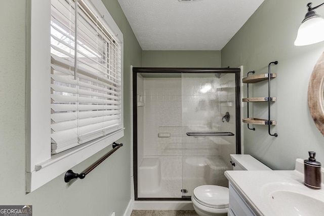 full bathroom with a stall shower, a textured ceiling, toilet, and vanity