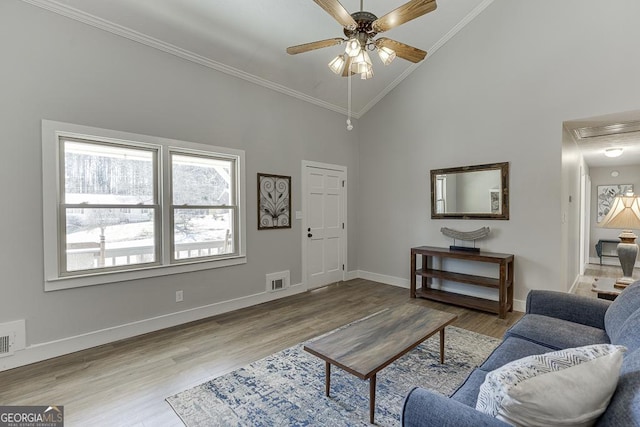 living area featuring ceiling fan, crown molding, baseboards, and wood finished floors