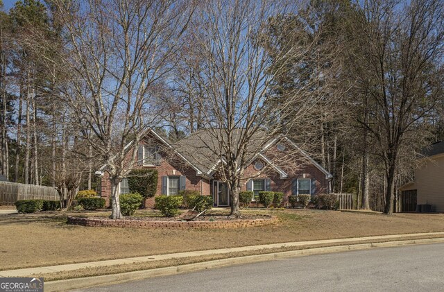 view of front facade featuring a front yard, fence, and brick siding