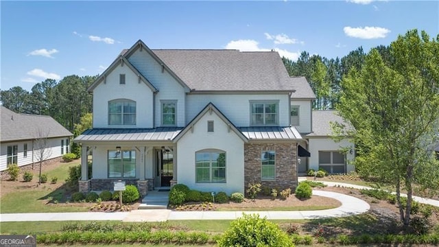 view of front of property with stone siding, metal roof, a standing seam roof, covered porch, and a front yard