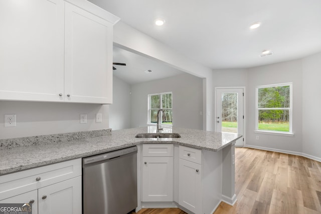 kitchen featuring light wood-style flooring, stainless steel dishwasher, white cabinets, a sink, and a peninsula