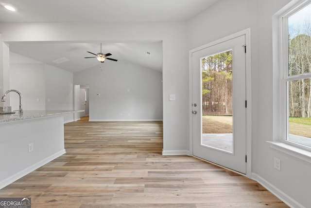 entryway featuring lofted ceiling, a healthy amount of sunlight, a sink, and light wood finished floors