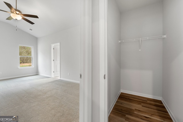 spacious closet with a ceiling fan, visible vents, vaulted ceiling, and carpet floors