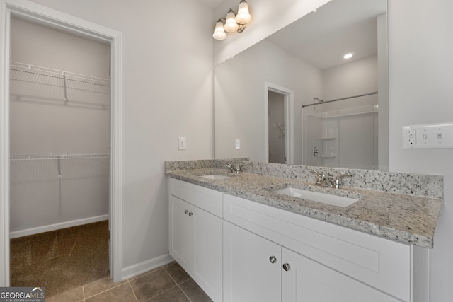 bathroom with double vanity, tile patterned flooring, walk in shower, and a sink