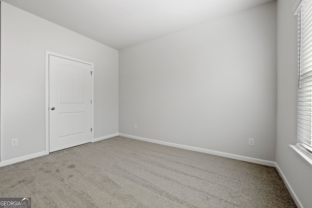 empty room featuring a wealth of natural light, carpet flooring, and baseboards