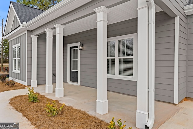 property entrance featuring covered porch, a shingled roof, and board and batten siding