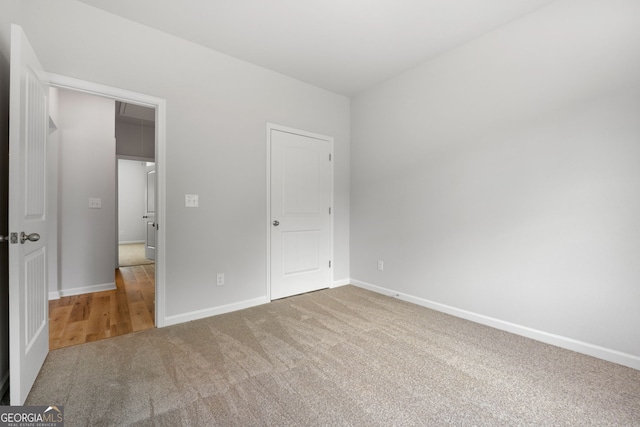 unfurnished bedroom with carpet flooring, attic access, and baseboards