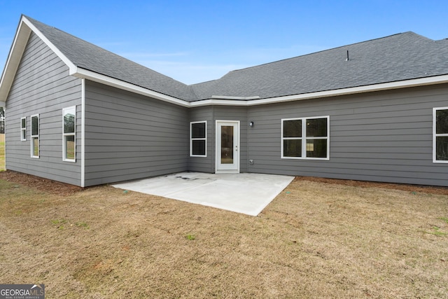 rear view of house featuring roof with shingles, a patio, and a yard