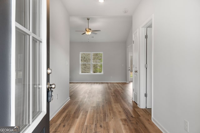 entryway featuring ceiling fan, wood finished floors, visible vents, baseboards, and vaulted ceiling