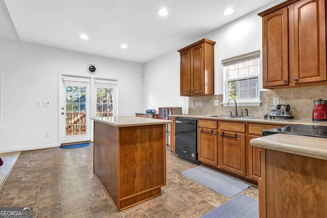 kitchen featuring decorative backsplash, dishwasher, a kitchen island, light countertops, and a sink