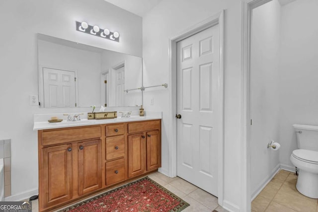 full bathroom featuring double vanity, toilet, a sink, tile patterned flooring, and baseboards