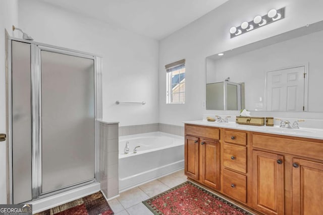 full bath with double vanity, a stall shower, tile patterned floors, a garden tub, and a sink