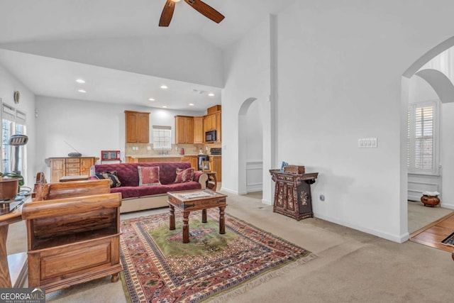 living area with high vaulted ceiling, ceiling fan, arched walkways, and baseboards