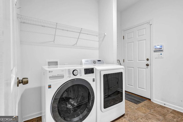 clothes washing area with laundry area, washing machine and dryer, and baseboards