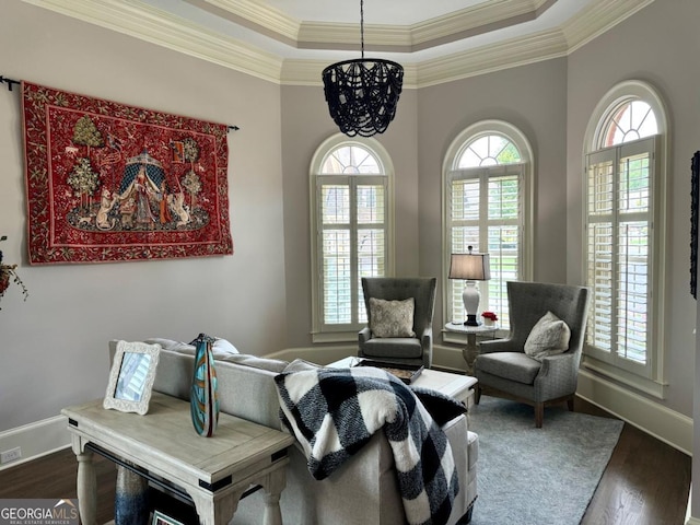 sitting room featuring dark wood finished floors, a raised ceiling, an inviting chandelier, ornamental molding, and baseboards