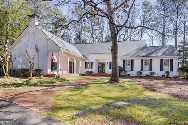 view of front of property with a front yard, roof with shingles, and a chimney