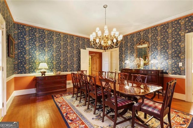 dining room with ornamental molding and wallpapered walls