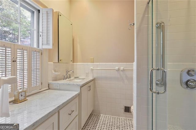 bathroom with a wainscoted wall, a stall shower, vanity, and tile walls