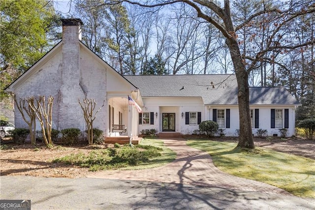 view of front of property featuring a front lawn, roof with shingles, and a chimney