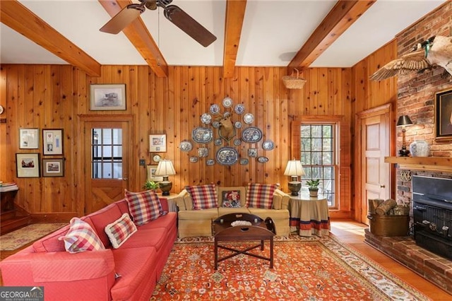 living room featuring beamed ceiling, wooden walls, and a ceiling fan