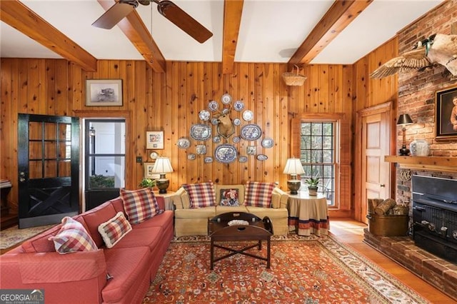 living room with wood finished floors, beam ceiling, wood walls, and a ceiling fan