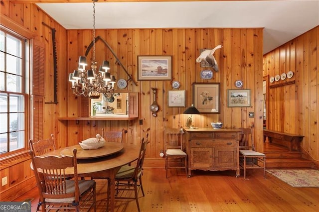 dining area featuring a wealth of natural light, a notable chandelier, wood walls, and hardwood / wood-style flooring