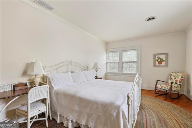 bedroom with baseboards, wood finished floors, visible vents, and ornamental molding