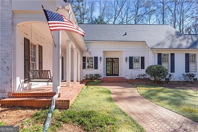 view of front of home with brick siding, a front lawn, and a shingled roof