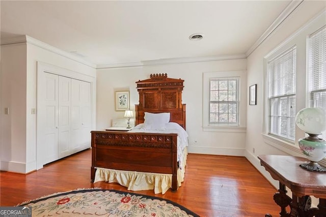 bedroom featuring crown molding, wood finished floors, and visible vents