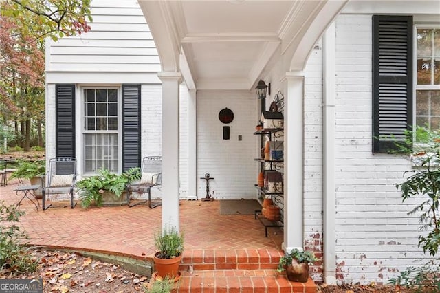 entrance to property featuring covered porch and brick siding