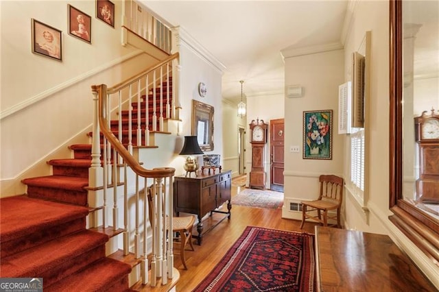 staircase with wood finished floors and ornamental molding