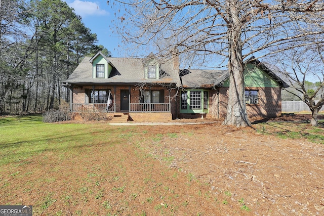 cape cod house with covered porch, a front lawn, and brick siding