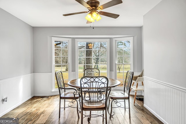 dining room with a wainscoted wall, ceiling fan, and wood finished floors