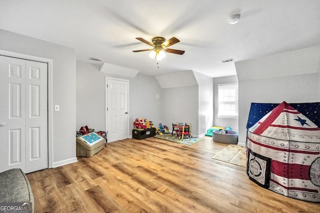 recreation room with ceiling fan, wood finished floors, visible vents, baseboards, and vaulted ceiling