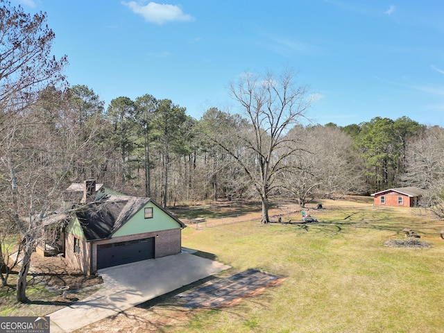 view of yard with a garage, driveway, and a forest view