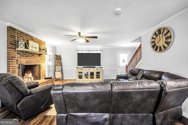 living area featuring a fireplace, ornamental molding, wood finished floors, baseboards, and stairs