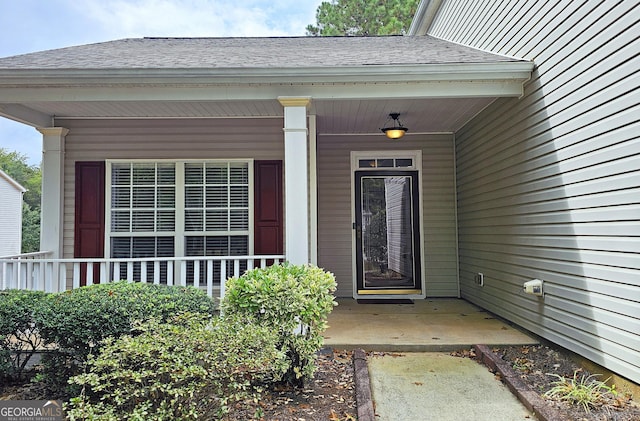 doorway to property featuring a shingled roof and covered porch