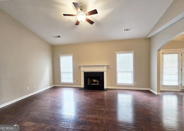 unfurnished living room with a fireplace with raised hearth, wood-type flooring, visible vents, and a ceiling fan