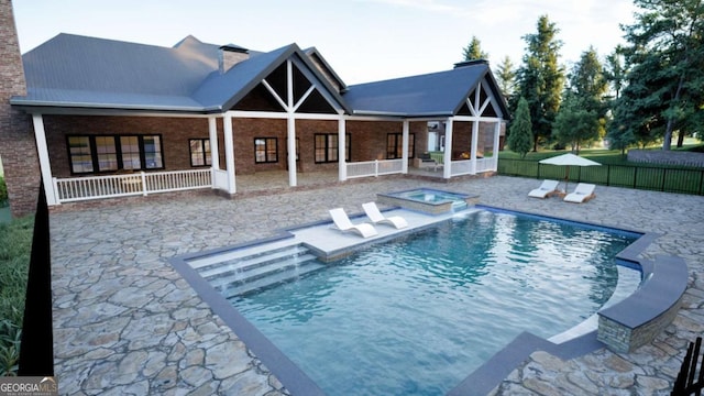 back of property featuring brick siding, a patio, a chimney, a pool with connected hot tub, and fence