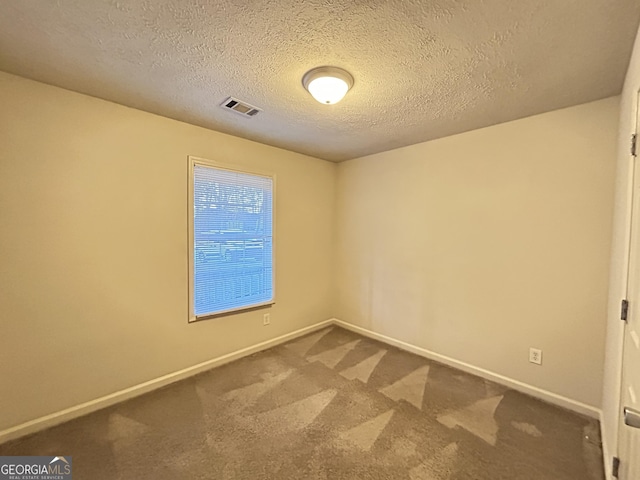 spare room featuring carpet floors, baseboards, visible vents, and a textured ceiling