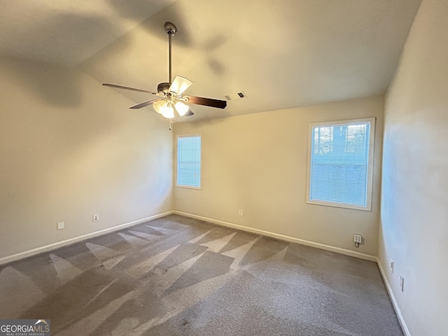 carpeted spare room featuring ceiling fan, visible vents, and baseboards