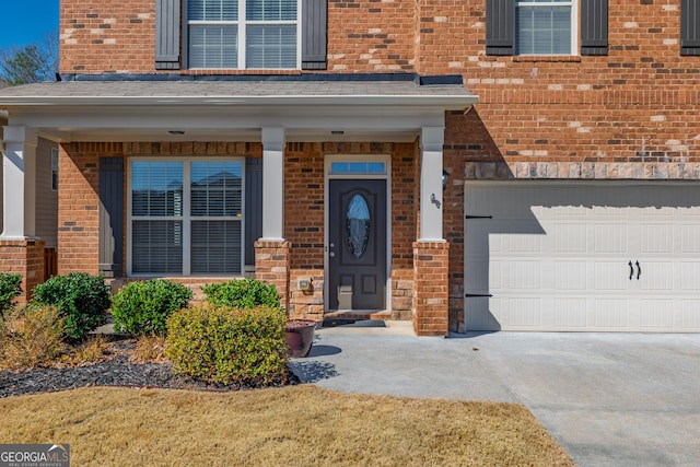 view of exterior entry featuring a garage and brick siding